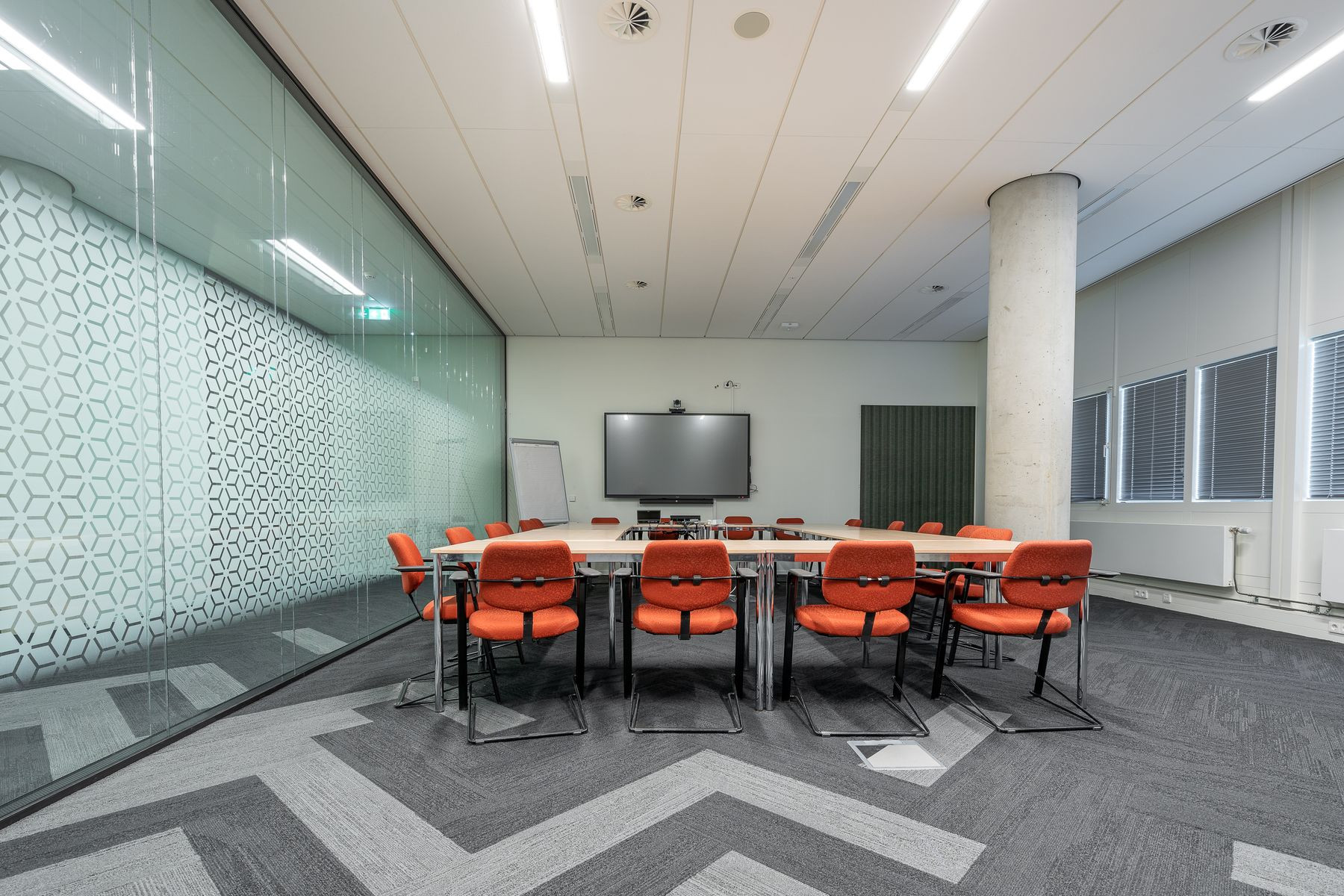 An empty meeting room with a long table and glass walls