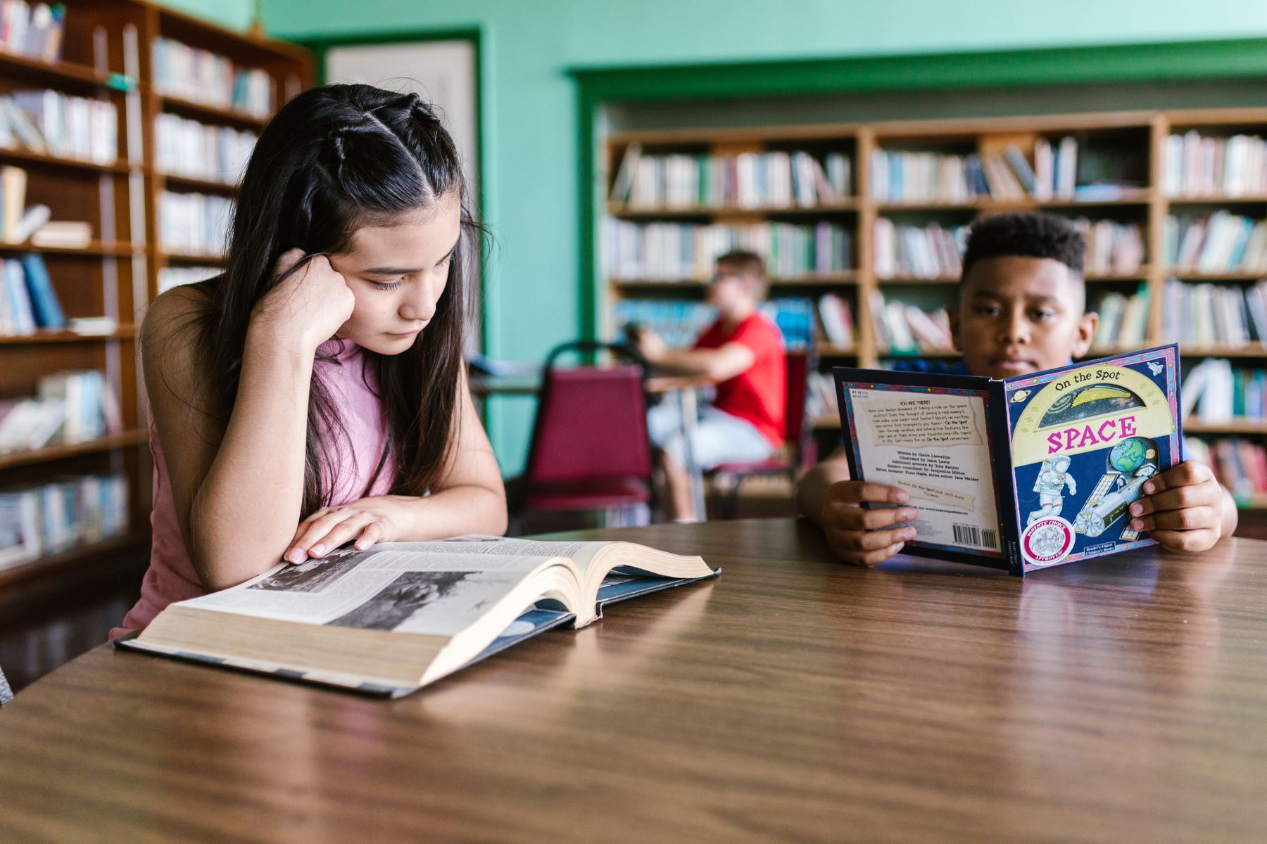 Students reading books at a table in a library